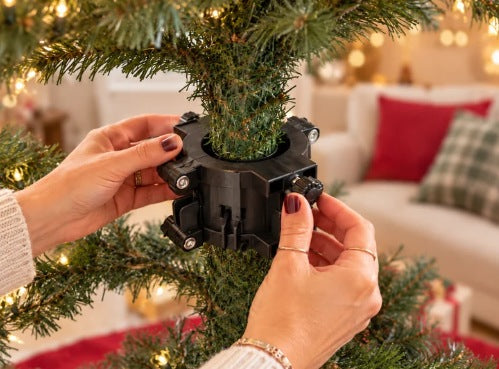 Hands fitting the adjustable train mount around a Christmas tree trunk