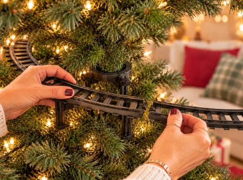 Hands snapping the train track pieces together around the tree